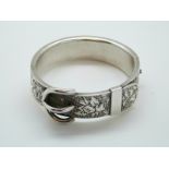 A white metal Victorian bangle with engraved foliate and buckle design