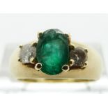 A 14ct gold ring set with an oval emerald and two diamonds, size M, 6.
