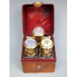 A late 19thC or early 20thC leather cased travelling set containing three glass bottles with floral