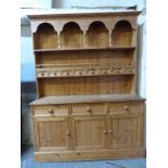 A pine dresser with plate rack above also having eight small drawers to top,