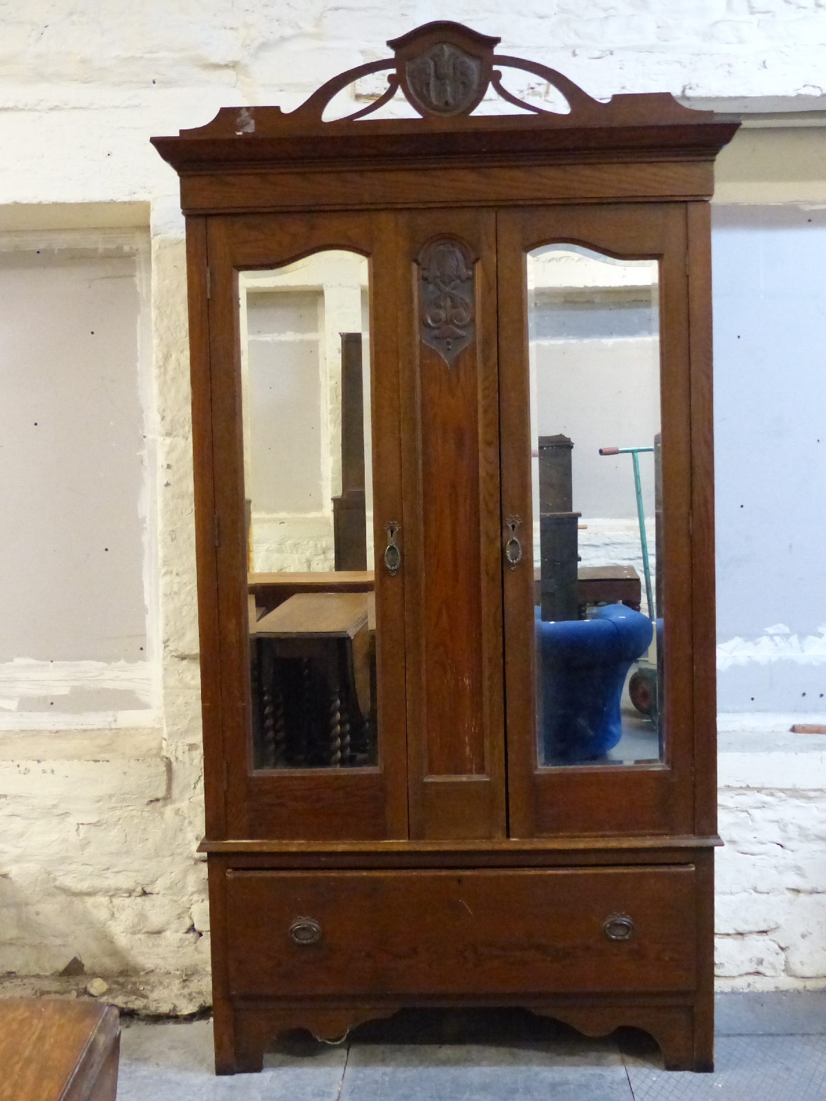 An oak mirror door wardrobe with single drawer below,