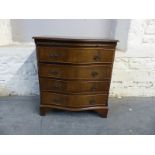 Small serpentine fronted chest of four drawers with brushing slide above,