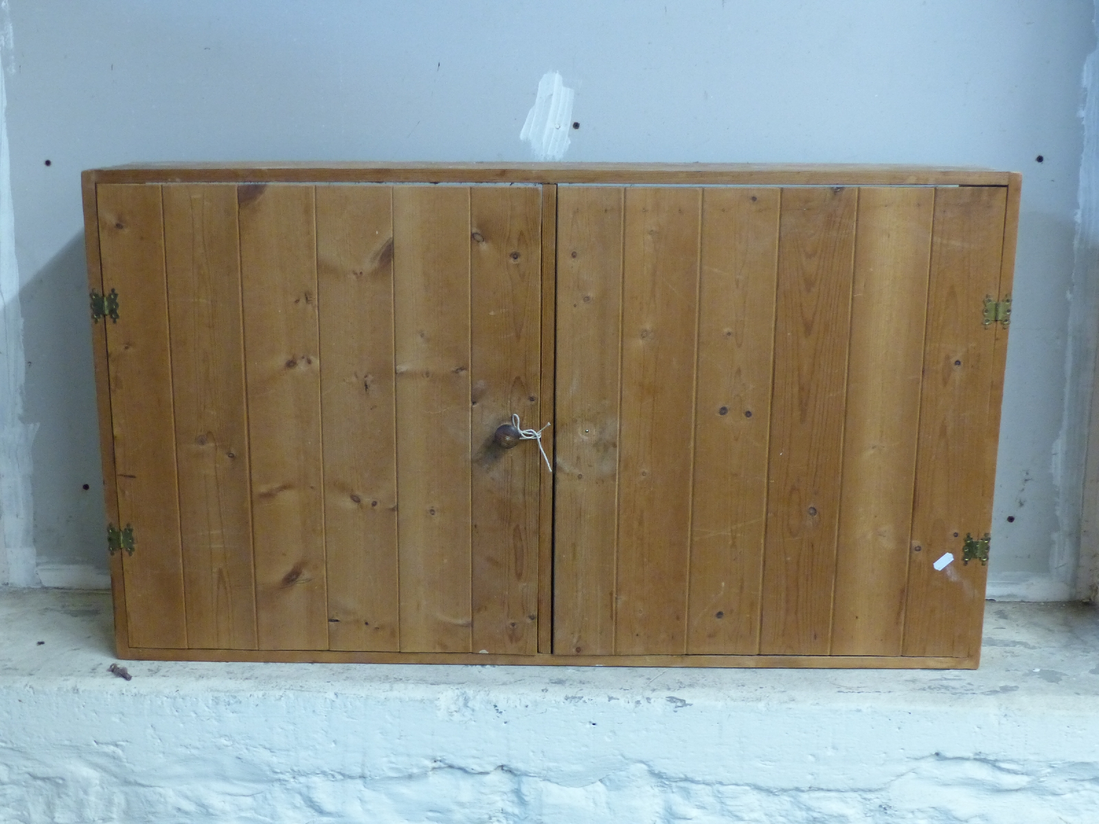 A pine two door wall mounted cupboard,