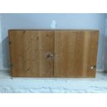 A pine two door wall mounted cupboard,