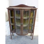 A late 19thC/early 20thC bow fronted corner cupboard with inlaid decoration,