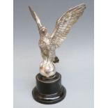 A car mascot formed as an eagle or similar bird mounted on a ball,