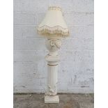 A faux carved stone plinth with lamp,