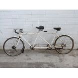A vintage tandem bicycle with white frame and drum brakes