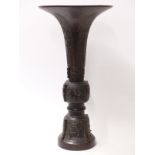 An 18th/19th Chinese bronze vase of gu form, the sides cast with bands of archaic style patterns,