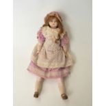 A wax headed doll with closed mouth, fixed blue eyes, long brown hair, wax limbs and soft body,