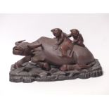 Chinese carved wooden water buffalo with figures on its back and bone teeth, on hardwood stand,