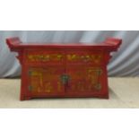 A Chinese sideboard with a red ground and lacquer decoration depiciting figures,