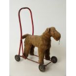 Blonde mohair straw filled child's push along dog on red metal frame, 38cm tall.