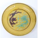 A 19thC Chinese dish with yellow ground decorated with aubergine and green dragons chasing a