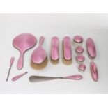 George V pink guilloché enamel dressing table set comprising hand mirror, three brushes,