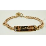 A yellow metal identity bracelet with gold flower charm set with a ruby,