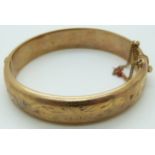 A 9ct gold bangle with engraved foliate decoration, 18.