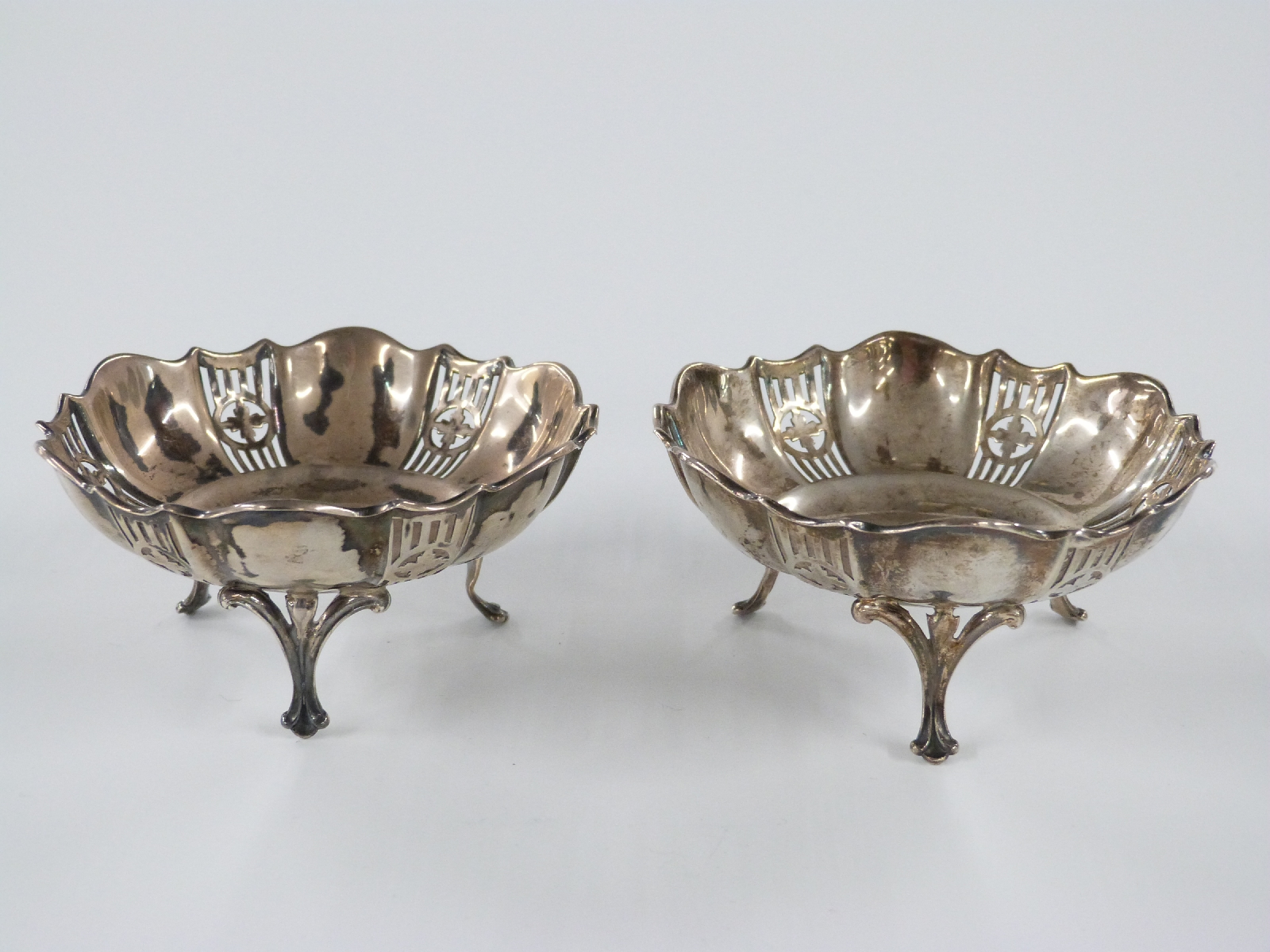A pair of George V hallmarked silver pierced bonbon dishes, raised on three feet, Birmingham 1915