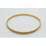 A 22ct gold bangle with cut out and textured detail, 12.5g