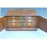 Oak cased 12 place setting canteen of cutlery with three drawers behind cupboard doors
