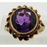 A 9ct gold ring set with a round cut amethyst with a twist border, size J