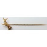 A yellow metal stick pin in the form of an antler with textured detail