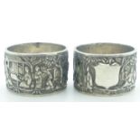 Pair of Chinese white metal napkin rings decorated with figures, buildings and trees, with Chinese