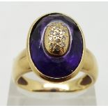 An 18ct gold ring set with a faceted amethyst and diamonds in an oval gold section to the centre,