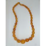 A Baltic amber necklace made up of graduated oval beads the largest bead 2.4 x 2cm, smallest 1 x 0.