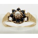 A 9ct gold ring set with a pearl surrounded by sapphires, size R