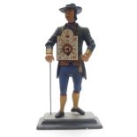 A vintage clock in the form of a man with walking stick holding clock weights