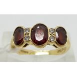 An 18ct gold ring set with three garnets and diamonds, size L