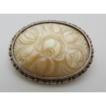 A silver brooch set with a carved mother of pearl plaque depicting flowers, 4.5 x 3.5cm