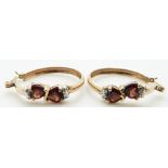 A pair of 10k gold earrings set with heart shaped garnets and diamonds