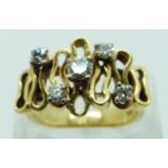 An 18ct gold ring set with five diamonds in an abstract design with textured band, the largest