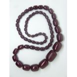 A large cherry amber necklace made up of graduated barrel shaped beads, 120g