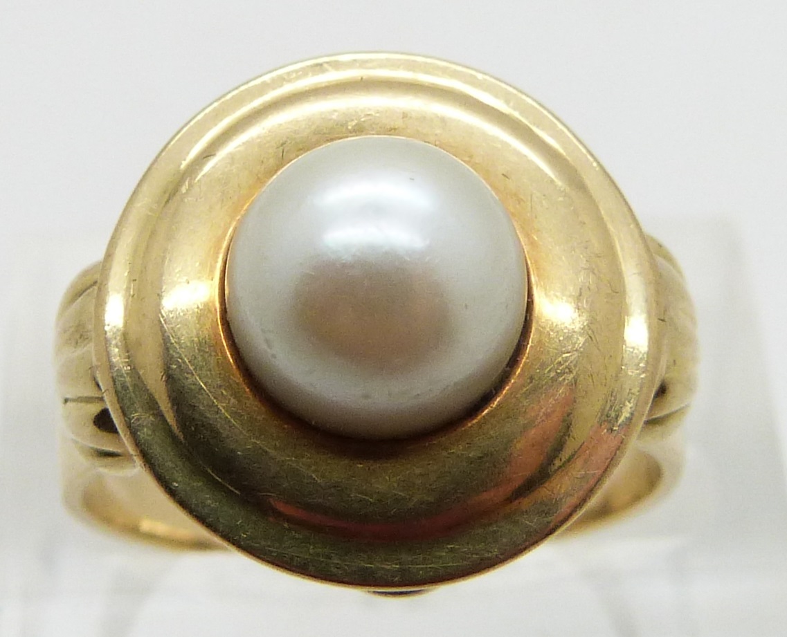 A 14ct gold ring set with a cultured pearl, with shell design to each shoulder, size O