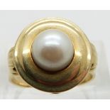 A 14ct gold ring set with a cultured pearl, with shell design to each shoulder, size O