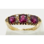 An 18ct gold ring set with three cushion cut rubies and six diamonds, size P