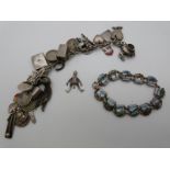 A silver/white metal charm bracelet with various charms including coins and enamel and a white metal