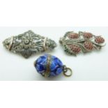 A silver egg pendant set with enamel and two silver brooches
