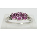 A 9ct white gold ring set with three oval pink sapphires and diamonds, size N