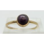 A gold ring set with a star ruby cabochon, size P