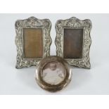 A pair of Edward VII hallmarked silver photograph frames with embossed decoration and easel backs,