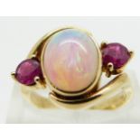 An 18ct gold ring set with an oval opal cabochon and two round cut rubies, size M