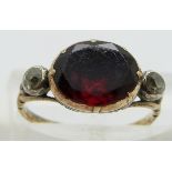 A Georgian ring set with a foiled garnet and an old cut diamond to each shoulder, size H