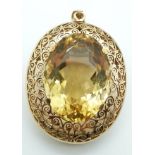 A 9ct gold pendant / brooch with scrolling and pierced border set with a 58ct citrine, with