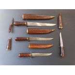 A set of five knives of graduated sizes. All in wooded sheaths. Largest 47cm, smallest 21cm.