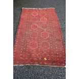 An Afghan rug, having Gul design and red ground, 180 x 111cm.