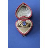 An unmarked yellow metal ring set central oval sapphire, in vintage heart shaped box.